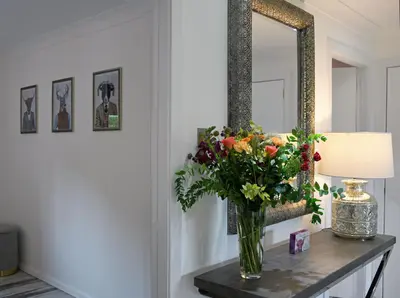 a vase of flowers on a table in front of a mirror at Gleneagles Luxury Apartment in Auchterarder