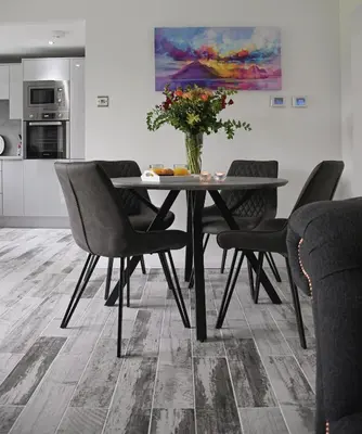 a dining room table with chairs and a vase with flowers at Gleneagles Luxury Apartment in Auchterarder