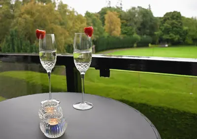 two wine glasses on a table with a view of a golf course at Gleneagles Luxury Apartment in Auchterarder