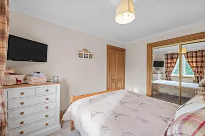 a bedroom with a bed and a dresser with a television at The Ploughman's Poet in Bathgate