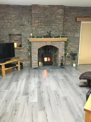 a living room with a stone fireplace and wooden floors at Ben Lomond Cottage in Gartocharn
