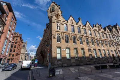a large brick building with a clock tower on a street at Merchant City Apartment in Glasgow
