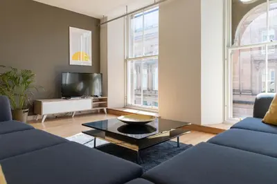 a living room with two blue couches and a coffee table at Merchant City Apartment in Glasgow