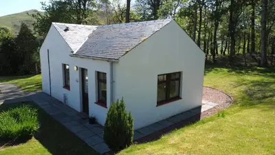 a small white house in a grassy field at Foxglove Cottage in Maybole