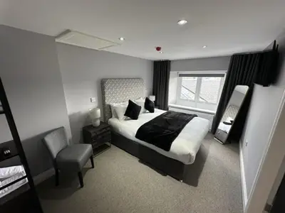 a bedroom with a bed and a chair and a window at Blackbull hotel in Tarbolton