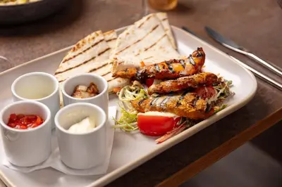a plate of food with chicken skewers and some dips at Blackbull hotel in Tarbolton