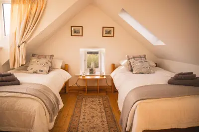 a attic room with two beds and a window at Auchnabreac Cottage in Carradale