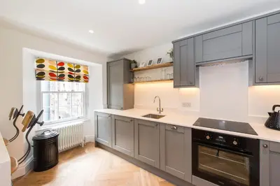 a kitchen with gray cabinets and a sink and a window at City Centre, Newly Refurbished Stylish Apartment in Edinburgh