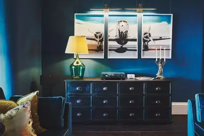 a bedroom with a dresser and a blue wall with pictures at No.26 By The Sea in Oban