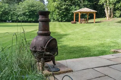 an old stove in a yard with a gazebo at 1-Bed Cabin 2 adults Wood Burning Hot Tub & Fire in Carluke