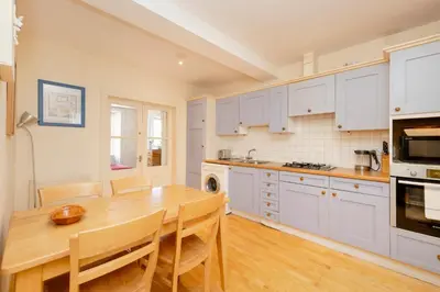 a kitchen with white cabinets and a wooden table at JOIVY Gorgeous 2-bed flat near Edinburgh Castle in Edinburgh