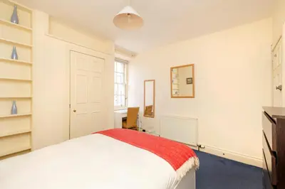 a bedroom with a white bed with a red blanket at JOIVY Gorgeous 2-bed flat near Edinburgh Castle in Edinburgh