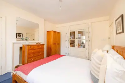 a bedroom with a white bed and a wooden dresser at JOIVY Gorgeous 2-bed flat near Edinburgh Castle in Edinburgh