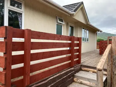 a wooden fence in front of a house at Lochay Lodges in Killin