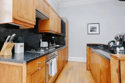 a kitchen with wooden cabinets and a stove top oven at JOIVY Lovely Flat in the Heart of Edinburgh in Edinburgh