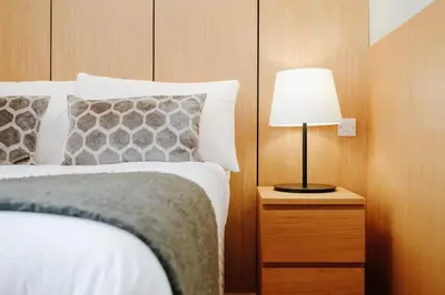 a bedroom with a bed and a lamp on a night stand at JOIVY Lovely Flat in the Heart of Edinburgh in Edinburgh