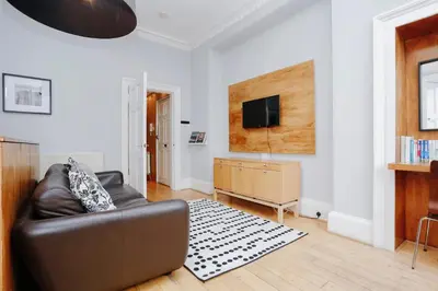a living room with a leather couch and a flat screen tv at JOIVY Lovely Flat in the Heart of Edinburgh in Edinburgh