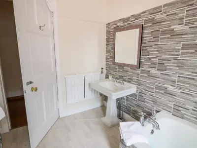 a bathroom with a sink and a tub and a mirror at Auchentroig House in Stirling