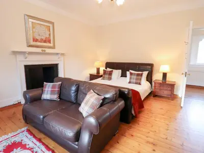 a bedroom with a bed and a leather couch at Auchentroig House in Stirling