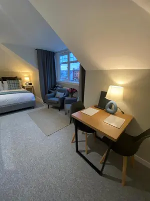 a hotel room with a bed and a desk and a bedroom at Peacock Guest House in Largs