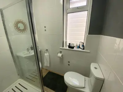 a white bathroom with a toilet and a shower at Peacock Guest House in Largs