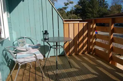 a patio with a table and chairs on a deck at Woodland Spruce Lodge in Killin