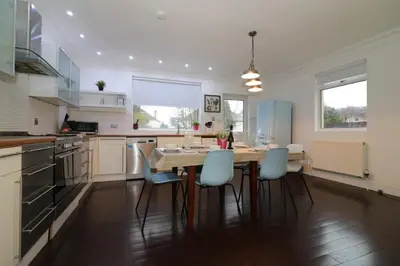 a kitchen with a wooden table and blue chairs at Signature - Moss View in Govan