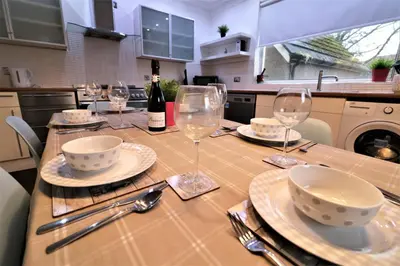 a table with glasses and plates and a bottle of wine at Signature - Moss View in Govan