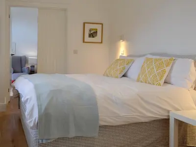 a bedroom with a large white bed with pillows at Printmakers Cottage in Bellanoch