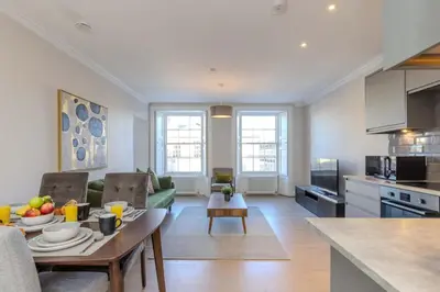 a kitchen and a living room with a table in a room at Dragon Suites - Edinburgh City Centre 2 Bed Apartment in Edinburgh