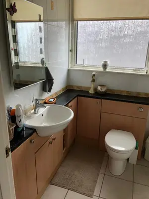 a bathroom with a sink and a toilet and a window at Limegrove Comfortable three bedroom house in Law