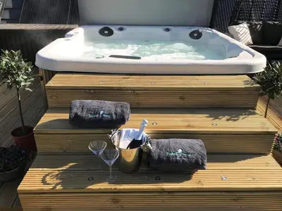 a jacuzzi tub on a wooden platform with two towels at Luxury Duplex - Sleeps 2 - Hot Tub - Parking in Glenfarg
