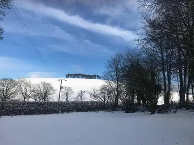 a snow covered field with trees and a hill in the background at Luxury Duplex - Sleeps 2 - Hot Tub - Parking in Glenfarg