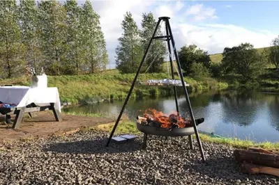 a fire grill next to a table and a lake at Luxury Duplex - Sleeps 2 - Hot Tub - Parking in Glenfarg