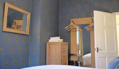 a bedroom with blue walls with a mirror and a dresser at Old Spittal Hospital Apartment - Free Parking in Stirling