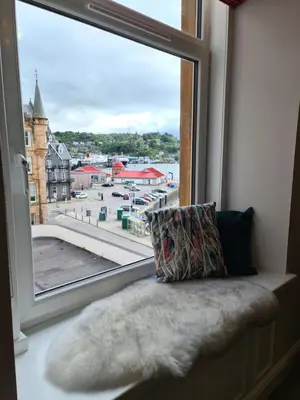 a window seat with a pillow and a view of a city at The Editor's Choice, Oban seafront apartment in Oban