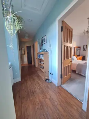 a room with a bedroom with a bed and a wooden floor at The Editor's Choice, Oban seafront apartment in Oban