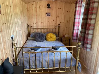 a bedroom with a bed in a wooden wall at Wee Highland Hideaway Hut in Dalmally