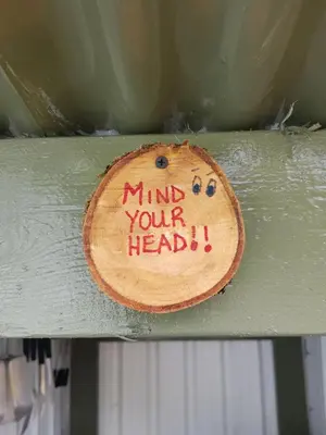 a piece of wood with the words mind your head written on it at Wee Highland Hideaway Hut in Dalmally