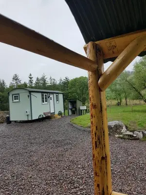 a large wooden structure with a trailer in the background at Wee Highland Hideaway Hut in Dalmally