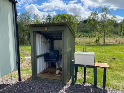 a shed with a sink and a blue chair in it at Wee Highland Hideaway Hut in Dalmally