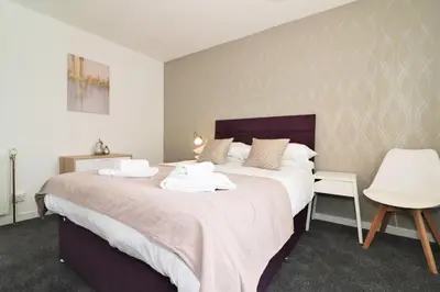 a bedroom with a large bed with white sheets at Signature - Troon View in East Kilbride