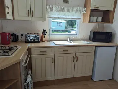 a kitchen with white cabinets and a sink and a microwave at 34 Glenfinart Park in Dunoon