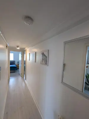 a white hallway with a large mirror on the wall at Glasgow City Centre Waterfront Apartment in Glasgow