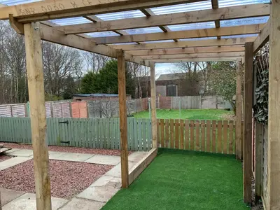 a wooden pergola in a yard with a fence at Nairoo in Balloch