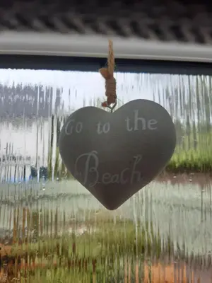 a heart hanging on a window with the words go to the beach at Ardgowan Cottage in Brodick