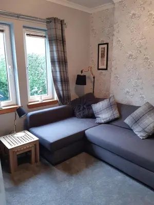 a living room with a blue couch and a table at Ardgowan Cottage in Brodick