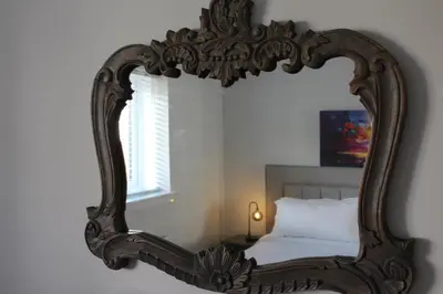 a mirror in a room with a bed and a window at Riverside Apartment in Ayr