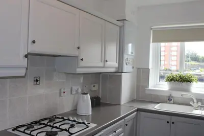 a kitchen with white cabinets and a stove top oven at Riverside Apartment in Ayr