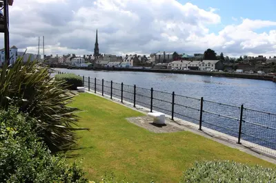 a river with a fence next to a body of water at Riverside Apartment in Ayr